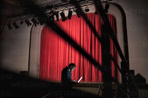 Director standing in front of stage at theatre using laptop stock photo