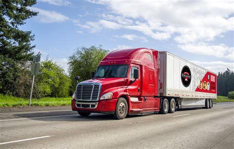 Red big rig popular bonnet semi truck transporting commercial cargo in dry van semi trailer ...