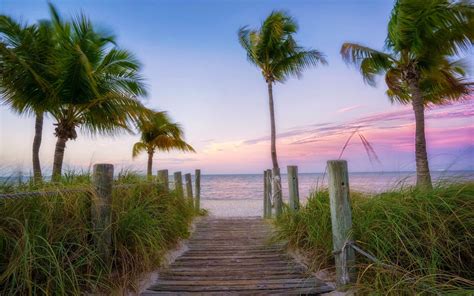 Download A Wooden Walkway Leading To The Beach At Sunset | Wallpapers.com