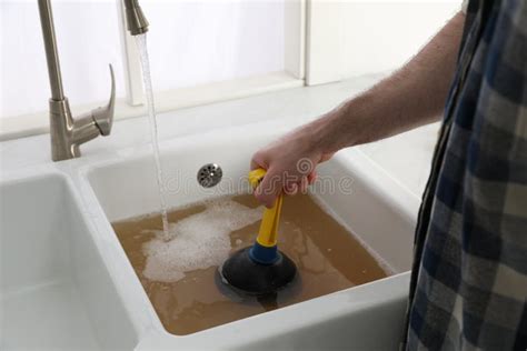 Man Using Plunger To Unclog Sink Drain in Kitchen, Closeup Stock Image ...