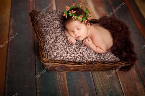 Beautiful newborn sleeping baby girl in a wicker basket on a wooden ...