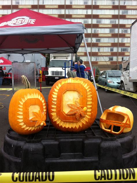 two carved pumpkins sitting on top of a black stand in front of a building