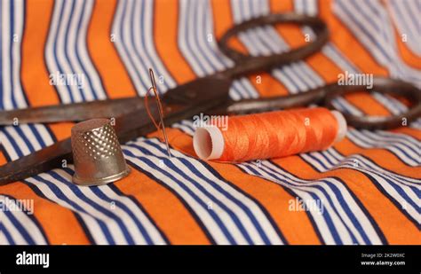 Orange Thread and Thimble on Orange and White Striped Fabric Stock Photo - Alamy