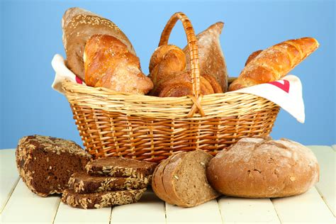 Composition with bread and rolls, in wicker basket on wooden table, on ...