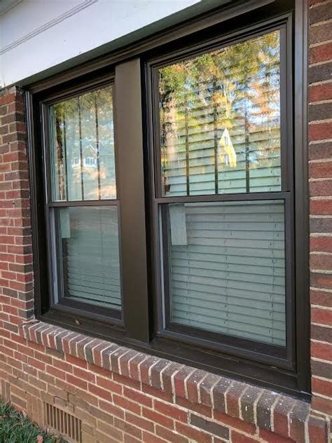 Bronze double hung windows with vertical grids in top sashes and bronze aluminum capping ar ...