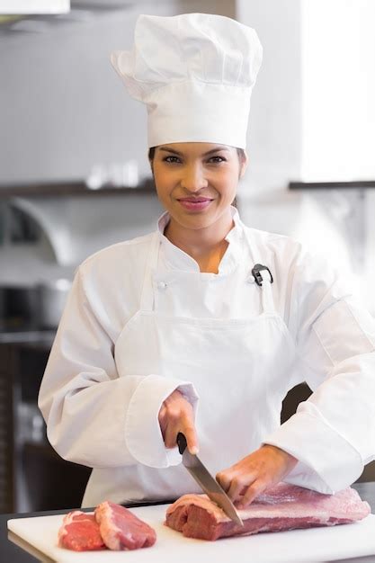 Premium Photo | Smiling female chef cutting meat in kitchen