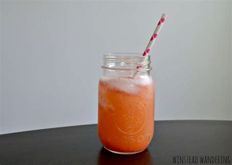 a mason jar filled with orange liquid and two straws