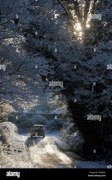 Car Driving On Snow Covered Road Near Beltingham Northumberland Stock