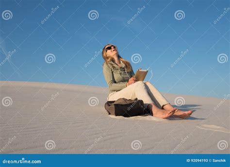 Woman Blonde Sits Alone In The Beach Chatting With Friends Using Digital Tablet Stock Image