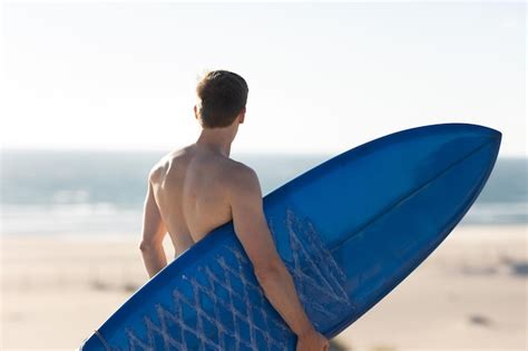 Premium Photo A Man With Naked Torso Standing On The Beach Holding A