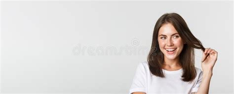 Close Up Of Flirty Attractive Brunette Girl Playing With Hair Strand Smiling And Looking