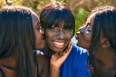 Three African American Friends Kissing Sitting On The Bench At The Park Stock Image Image Of