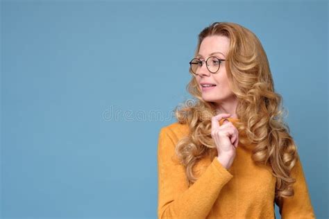 Mature Woman With Glasses And Long Blonde Hair Standing Isolated Over Blue Wall Stock Photo