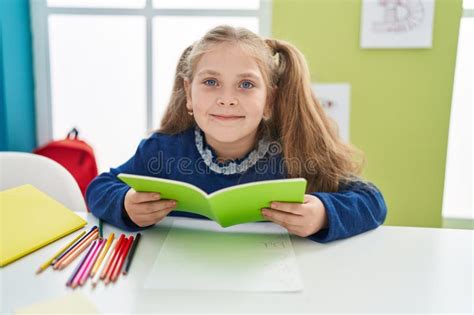 Adorable Blonde Girl Student Smiling Confident Reading Book At Classroom Stock Photo Image Of
