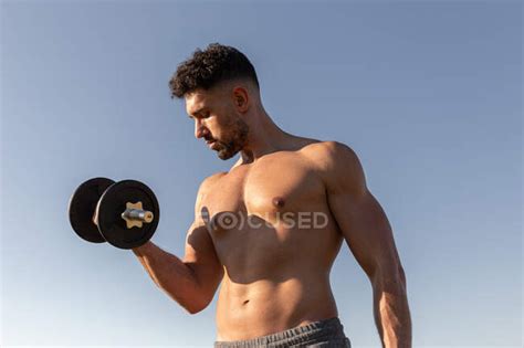 Low Angle Of Handsome Male Athlete With Naked Torso Doing Exercises With Dumbbells While