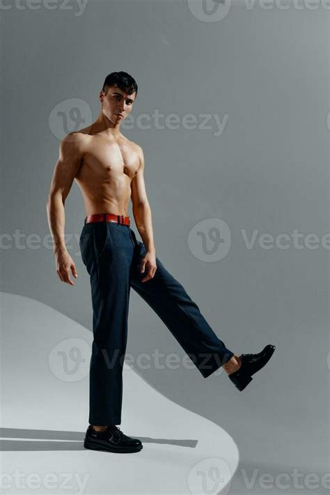 Portrait Of A Man In Jeans Patent Leather Shoes On A Gray Background Naked Torso Stock
