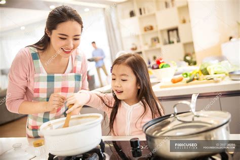 Happy asian mother and daughter cooking together in kitchen