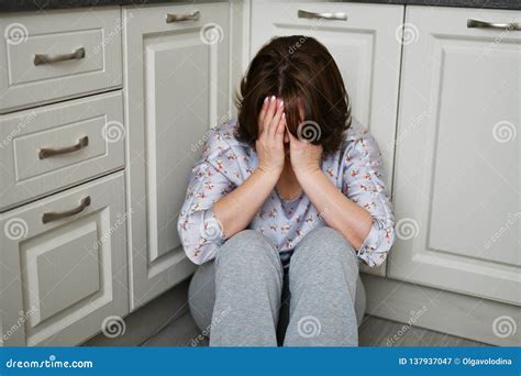 Woman Is Sitting On Kitchen Floor Covering Her Face With Her Hands