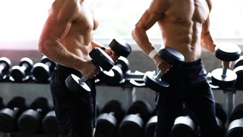 Premium Photo | Young Man Naked bodybuilder exercising lifting with dumbbell at gym. .Gym
