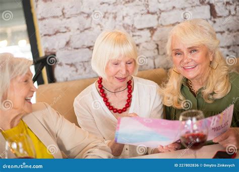 Three Mature Women Sitting At The Table And Looking Excited Stock Photo Image Of Wellbeing