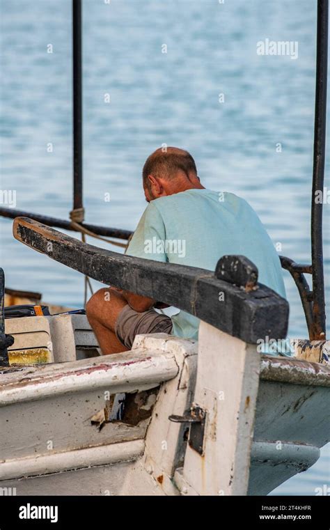 Old Greek Fisherman Sitting On A Traditional Fishing Boat In The Ionian