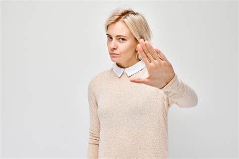Premium Photo Blonde Woman Showing Stop Gesture With Hand On A Light Background