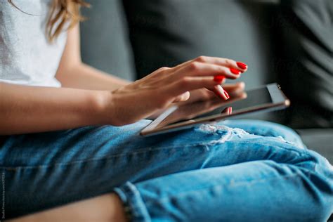 Brunette On The Sofa Reading A Digital Tablet By Stocksy Contributor