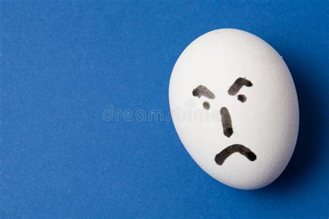 Egg With An Angry Face On Blue Background With Copy Space Stock Photo