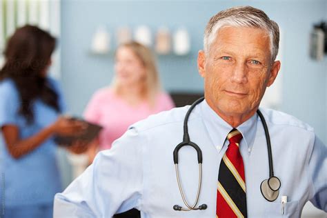 Exam Room Cheerful Mature Doctor By Stocksy Contributor Sean Locke Stocksy