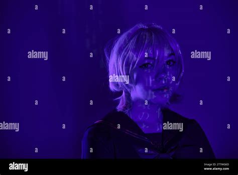 Portrait Of Charming Female Cosplayer In Blonde Wig With Hieroglyphs Projection In Blue Neon