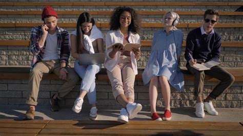 Group Of Young People Sitting Together Doing Different Things Stock