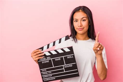 Joven Latina Sosteniendo Claqueta Aislado Sobre Fondo Rosa Mostrando El N Mero Uno Con El Dedo