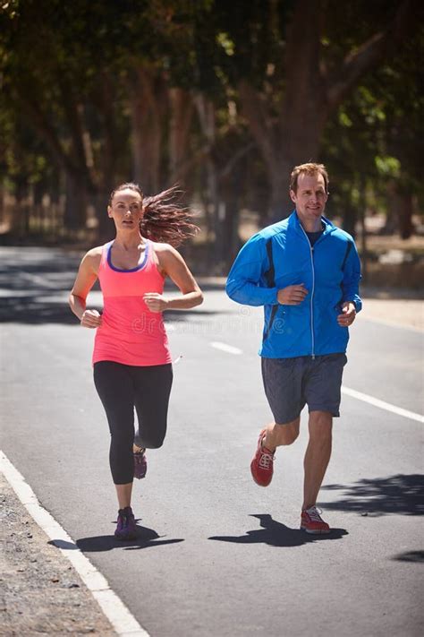 Hitting the Streets. Full Length Shot of a Couple Jogging on a Road ...