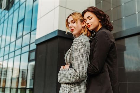 Dos Amigas Bonitas Posando Cerca De Un Edificio De Cristal Pareja De Chicas Lesbianas Gay
