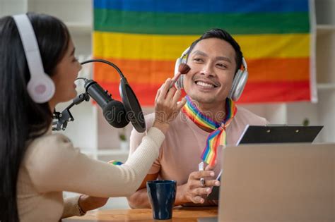 A Joyful Asian Gay Man Radio Host Is Being Made Up By A Female Guest In His Radio Show Stock