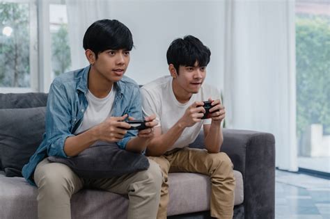 Joven pareja gay asiática juega juegos en casa hombres adolescentes coreanos lgbtq usando