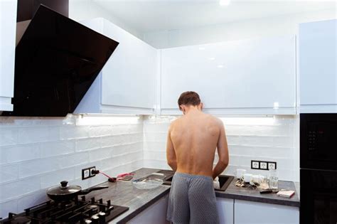 Premium Photo Man With A Naked Torso Cooks In The Kitchen The Husband Does The Housework