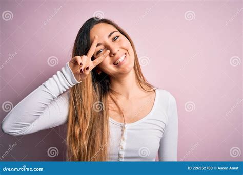 Jeune Belle Femme Blonde Aux Yeux Bleus Portant Un Tshirt Blanc Sur Fond Rose Faisant Symbole De