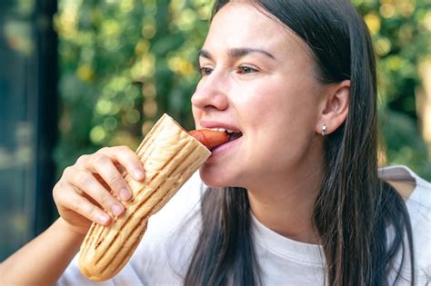 Uma Jovem Mulher Come Um Cachorro Quente Em Um Terra O De Caf Foto