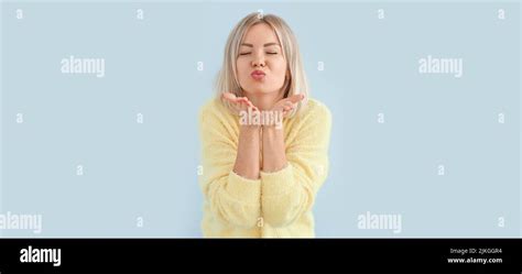 Portrait Of Beautiful Blonde Woman Blowing Kiss Against Light Background Stock Photo Alamy