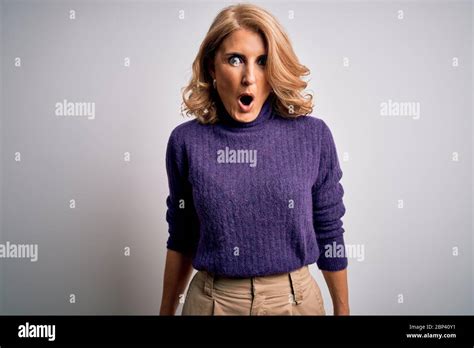 Middle Age Beautiful Blonde Woman Wearing Purple Turtleneck Sweater Over White Background Afraid