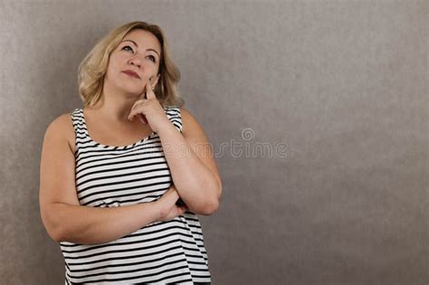 Portrait Of Blonde Plus Size Woman On Grey Background Looking Up And