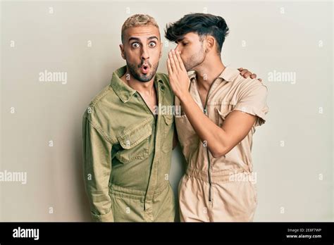 Homosexual Gay Couple Standing Together Wearing Casual Jumpsuit Hand On Mouth Telling Secret