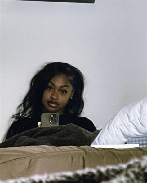 A Woman Laying In Bed Looking At Her Cell Phone