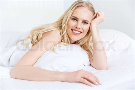 Beautiful Blonde Girl Smiling At Camera While Lying On Bed Stock Image Colourbox