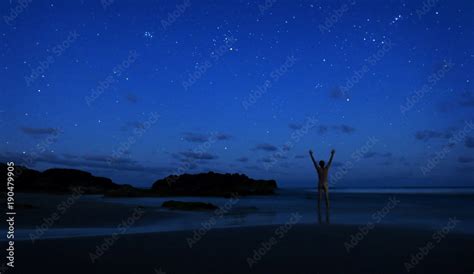 Naked Man Stands Alone On Beach At Night To Celebrate The Clear Sky Of Stars With Hands In The