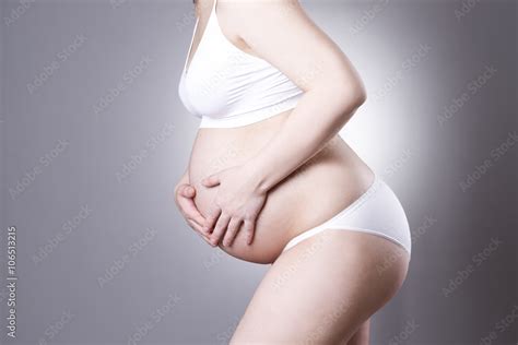Caucasian Pregnant Woman In White Lingerie With Abdominal Pain On Gray Studio Background Stock