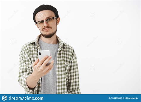 Indifferent Male Young Snob In Glasses And Beanie With Beard Holding