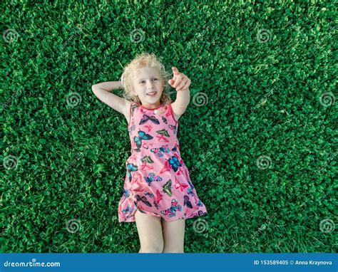 Fille De Sourire Caucasienne Blonde Dans La Robe Rose Rouge Se Trouvant
