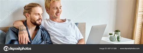 Happy Tattooed Gay Man Embracing Bearded Boyfriend While Watching Film Stock Photo